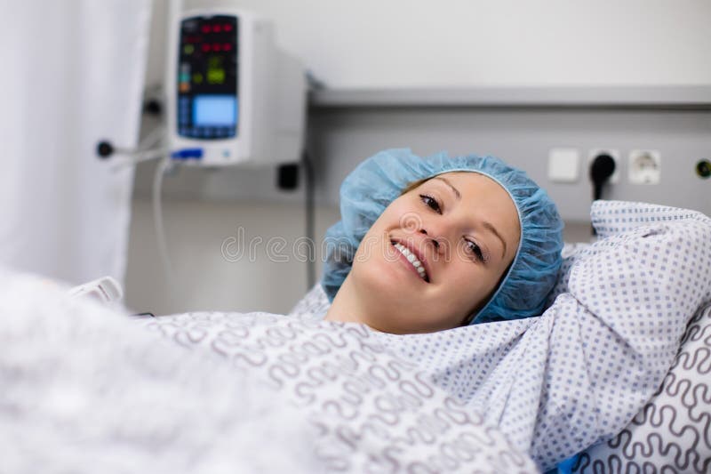 Jonge vrouw in de ruimte van de het ziekenhuisterugwinning na chirurgie stock foto Jonge vrouw in de ruimte van de het ziekenhuisterugwinning na chirurgie stock foto