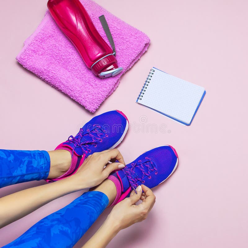 Jonge vrouw in de sportieve blauwe tennisschoenen van het beenkappenkant, die voor opleiding voorbereidingen treffen Toebehoren v stock afbeeldingen Jonge vrouw in de sportieve blauwe tennisschoenen van het beenkappenkant, die voor opleiding voorbereidingen treffen Toebehoren v stock afbeeldingen