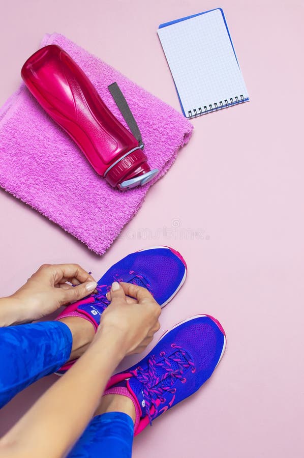 Jonge vrouw in de sportieve blauwe tennisschoenen van het beenkappenkant, die voor opleiding voorbereidingen treffen Toebehoren v royalty-vrije stock fotografie Jonge vrouw in de sportieve blauwe tennisschoenen van het beenkappenkant, die voor opleiding voorbereidingen treffen Toebehoren v royalty-vrije stock fotografie