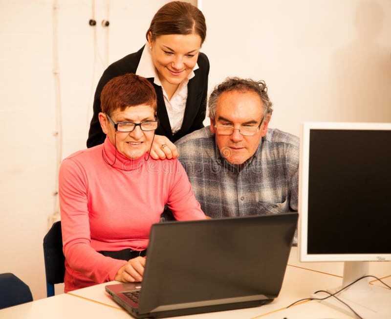 Jonge vrouw die bejaard paar van computervaardigheden onderwijzen Intergen royalty-vrije stock afbeeldingen Jonge vrouw die bejaard paar van computervaardigheden onderwijzen Intergen royalty-vrije stock afbeeldingen