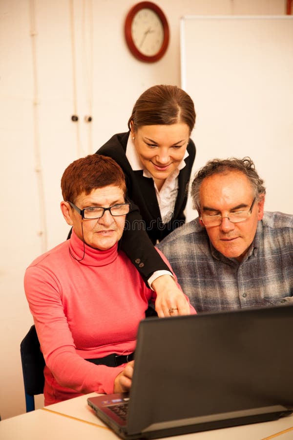 Jonge vrouw die bejaard paar van computervaardigheden onderwijzen Intergen stock fotografie Jonge vrouw die bejaard paar van computervaardigheden onderwijzen Intergen stock fotografie