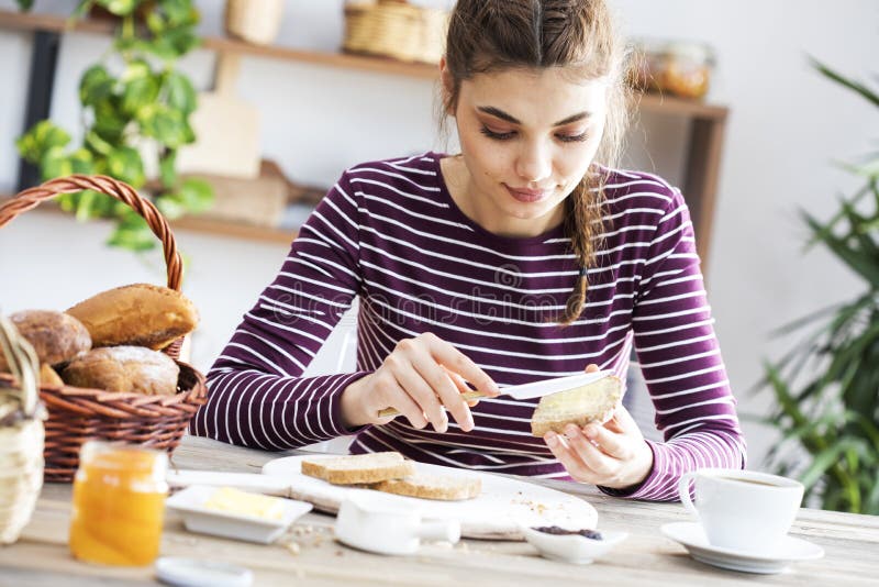 Jonge vrouw die brood met boter eten stock foto Jonge vrouw die brood met boter eten stock foto