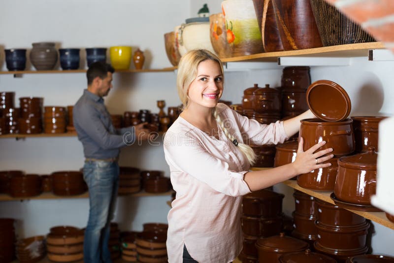Jonge vrouw die ceramische schotelwaren in atelier selecteren stock fotografie Jonge vrouw die ceramische schotelwaren in atelier selecteren stock fotografie