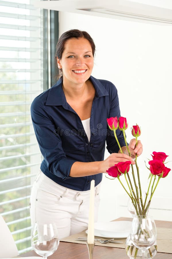 Jonge vrouw die de lijst van het bloemendiner schikken stock afbeelding Jonge vrouw die de lijst van het bloemendiner schikken stock afbeelding