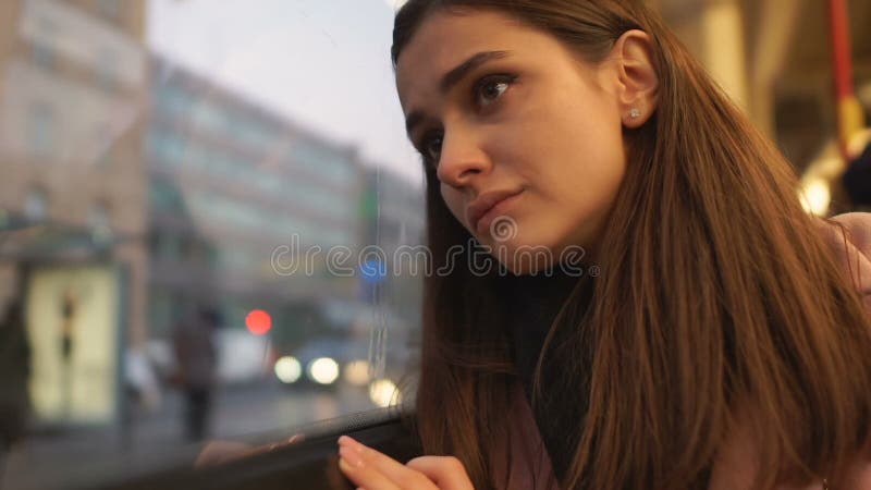 Jonge vrouw die droevig uit busvenster, die aan depressie en eenzaamheid lijden kijken