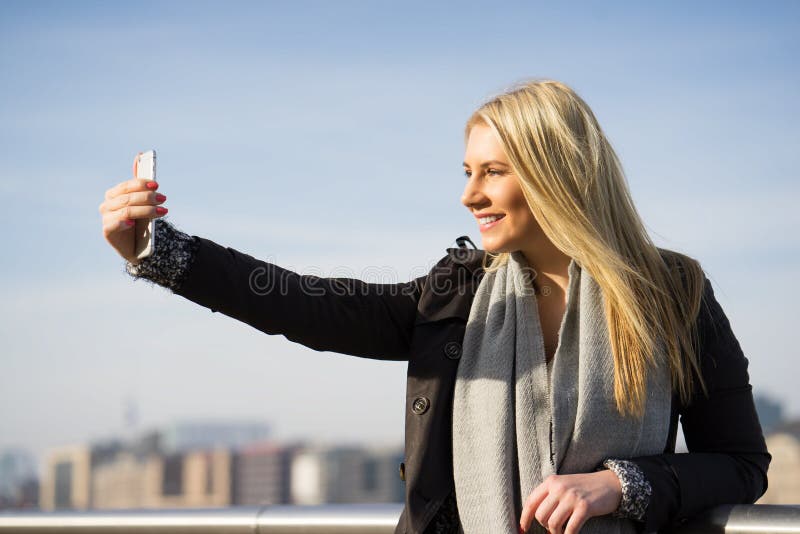 Jonge vrouw die een selfie in de de herfstzon nemen stock afbeeldingen Jonge vrouw die een selfie in de de herfstzon nemen stock afbeeldingen