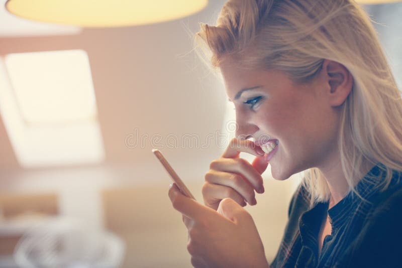 Jonge Vrouw die Haar Mobiele Telefoon bekijkt stock afbeelding Jonge Vrouw die Haar Mobiele Telefoon bekijkt stock afbeelding