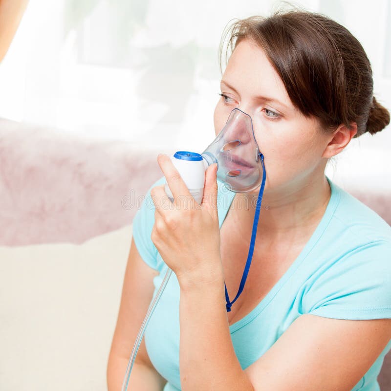 Jonge vrouw die inhalatie met een verstuiver thuis doen stock fotografie Jonge vrouw die inhalatie met een verstuiver thuis doen stock fotografie