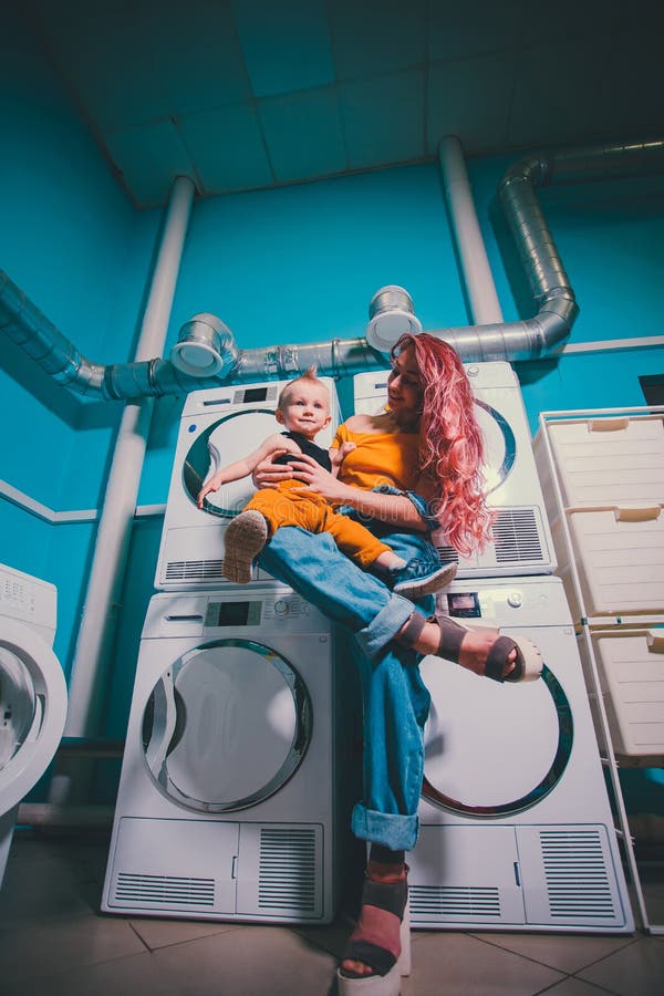 Jonge vrouw die kleding zoekt in wasmachinekamer bij de lancering stock afbeeldingen Jonge vrouw die kleding zoekt in wasmachinekamer bij de lancering stock afbeeldingen