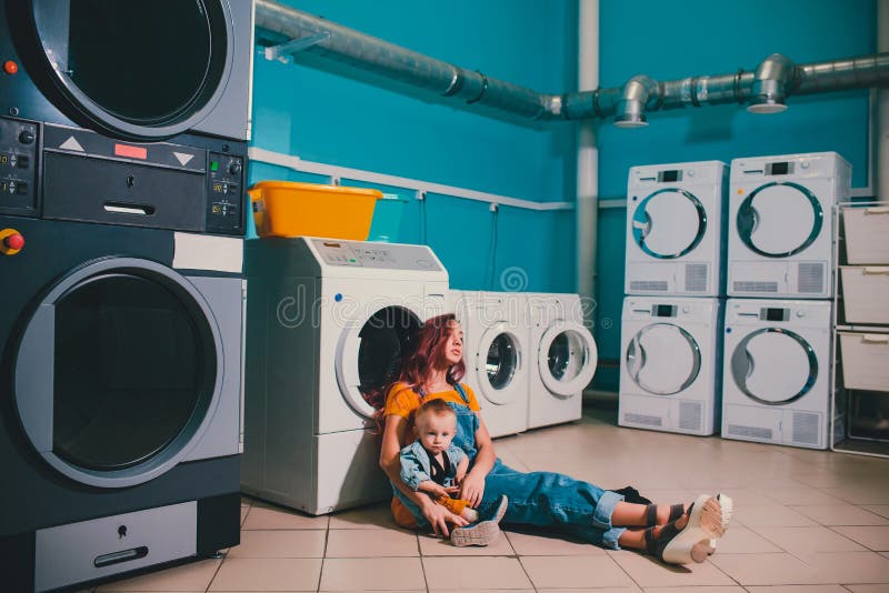 Jonge vrouw die kleding zoekt in wasmachinekamer bij de lancering stock afbeeldingen Jonge vrouw die kleding zoekt in wasmachinekamer bij de lancering stock afbeeldingen