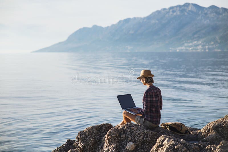 Jonge vrouw die laptop computer op een strand met behulp van Freelance het Werkconcept