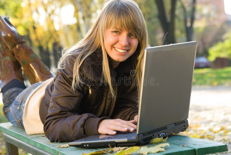 Jonge vrouw die met laptop in stadspark werkt
