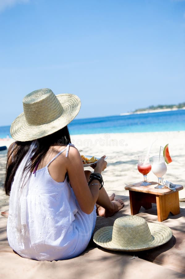 Jonge vrouw die op het strand eet stock fotografie Jonge vrouw die op het strand eet stock fotografie