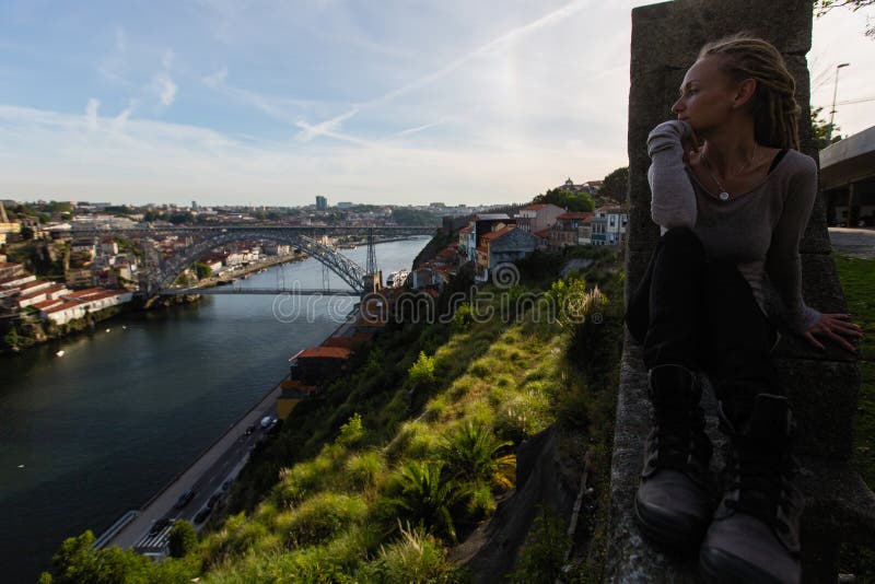 Jonge vrouw die tegenover Dom Luis I brug op Douro-rivier, Porto zitten stock afbeeldingen Jonge vrouw die tegenover Dom Luis I brug op Douro-rivier, Porto zitten stock afbeeldingen