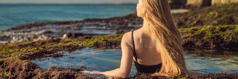 Young woman tourist on Pantai Tegal Wangi Beach sitting in a bath of sea water, Bali Island, Indonesia. Bali Travel Concept. BANNER, LONG FORMAT. Young woman tourist on Pantai Tegal Wangi Beach sitting in a bath of sea water, Bali Island, Indonesia. Bali Travel Concept. BANNER, LONG FORMAT