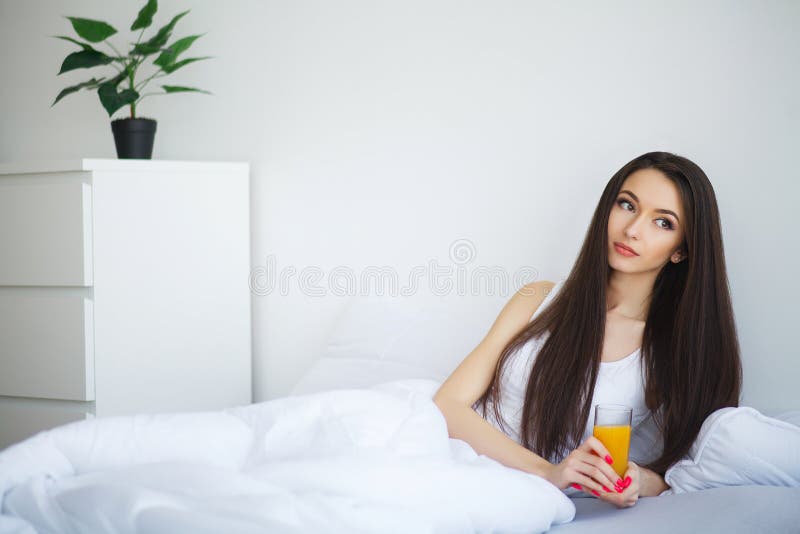 Jonge vrouw die van een glas jus d'orange in de ochtend genieten als s royalty-vrije stock fotografie Jonge vrouw die van een glas jus d'orange in de ochtend genieten als s royalty-vrije stock fotografie