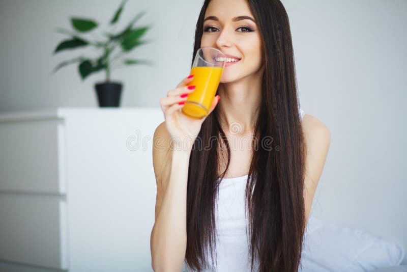 Jonge vrouw die van een glas jus d'orange in de ochtend genieten als s stock foto's Jonge vrouw die van een glas jus d'orange in de ochtend genieten als s stock foto's