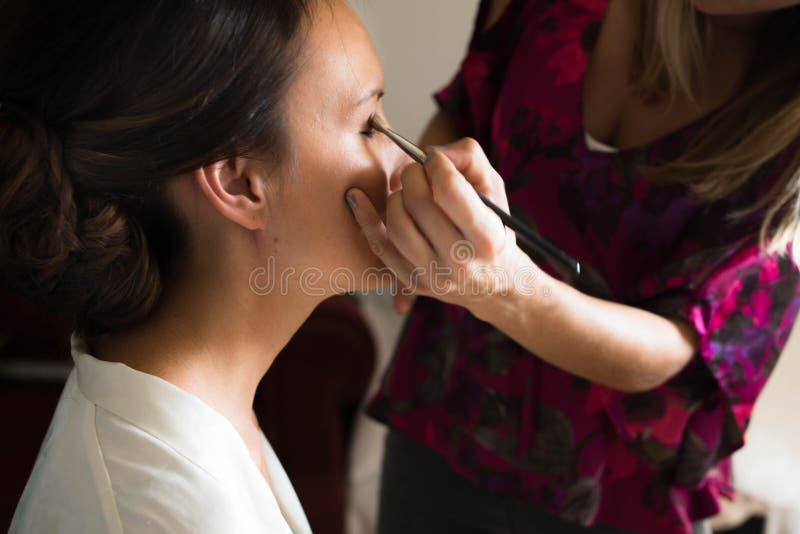 Jonge vrouw die voor haar huwelijk met een make-upkunstenaar voorbereidingen treffen stock afbeelding Jonge vrouw die voor haar huwelijk met een make-upkunstenaar voorbereidingen treffen stock afbeelding