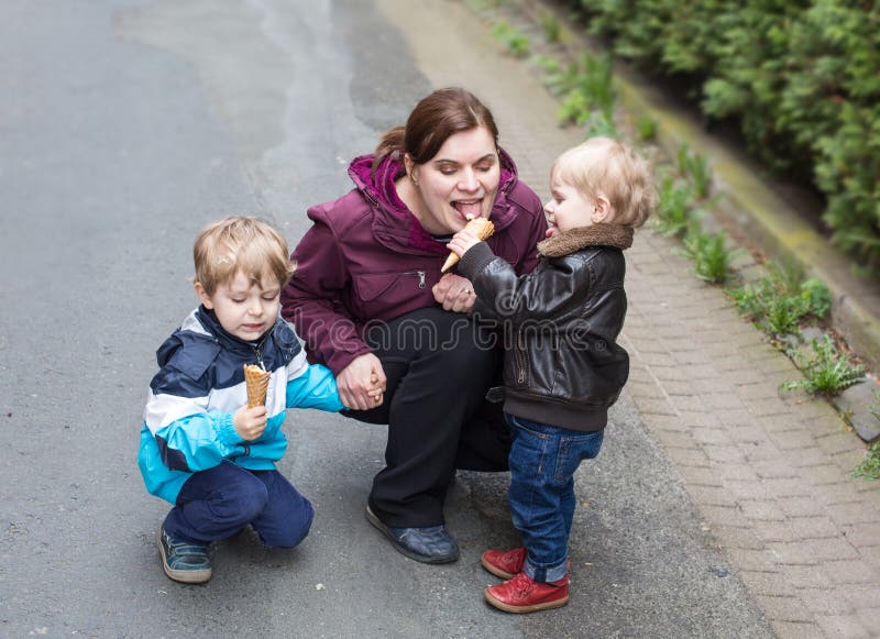 Jonge vrouw en twee kleine jongens die roomijs eten stock afbeelding Jonge vrouw en twee kleine jongens die roomijs eten stock afbeelding