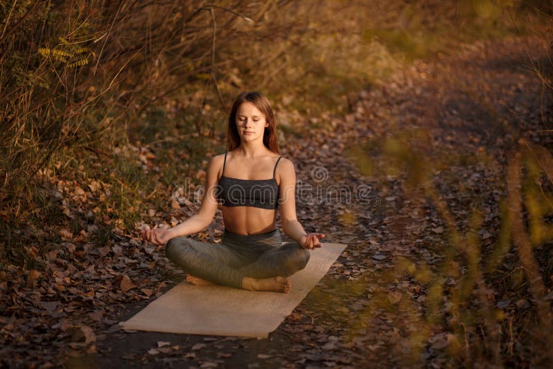 Jonge vrouw het praktizeren yogaoefening in de herfstpark met gele bladeren Sporten en recreatielevensstijl stock fotografie Jonge vrouw het praktizeren yogaoefening in de herfstpark met gele bladeren Sporten en recreatielevensstijl stock fotografie