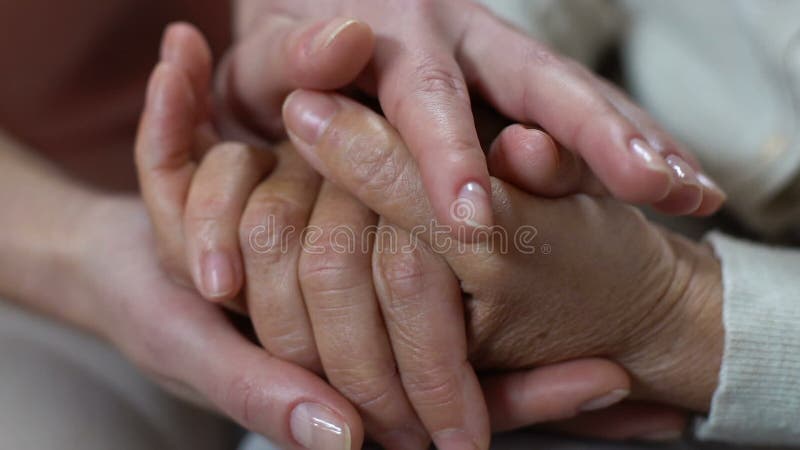 Jonge vrouw het strijken handen die van gepensioneerde, voor oude ouders, medeleven geven