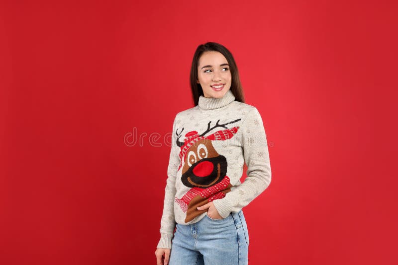 Jonge vrouw in een kersttrui op rode achtergrond stock foto