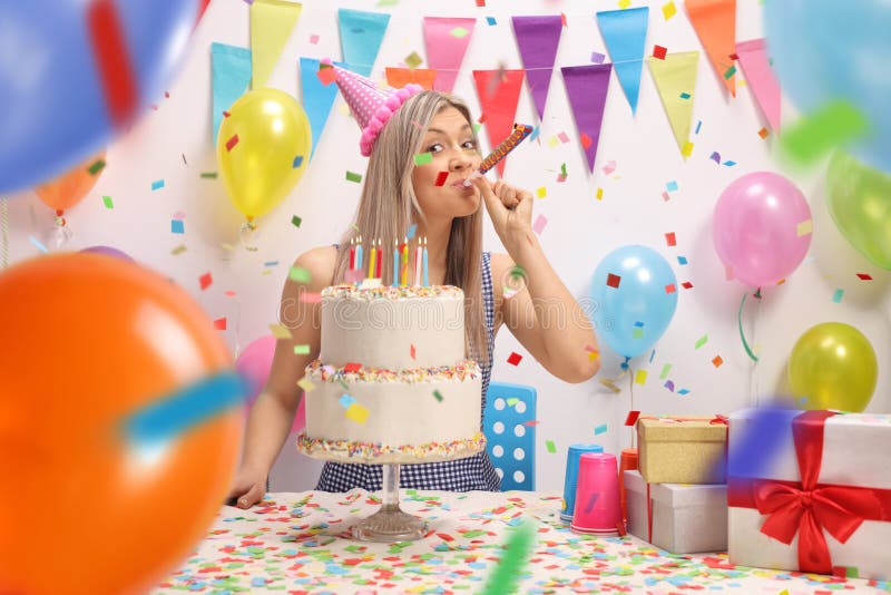 Jonge vrouw met een verjaardagscake die een partijhoorn blazen royalty-vrije stock fotografie Jonge vrouw met een verjaardagscake die een partijhoorn blazen royalty-vrije stock fotografie