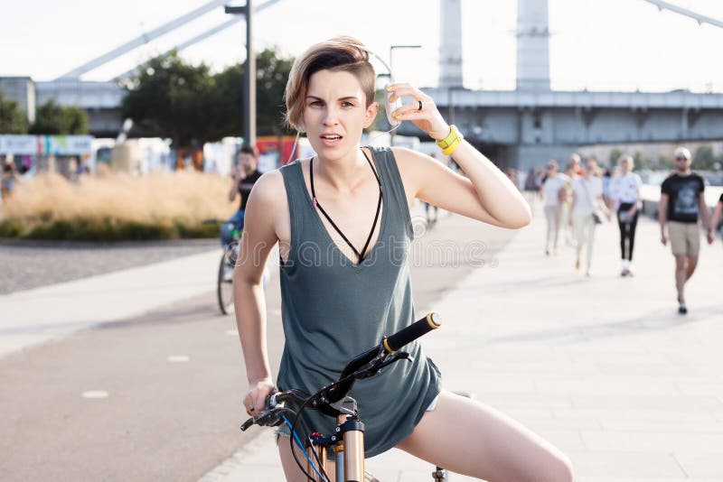 Jonge vrouw met fiets en hoofdtelefoons op stadsstraat stock fotografie Jonge vrouw met fiets en hoofdtelefoons op stadsstraat stock fotografie