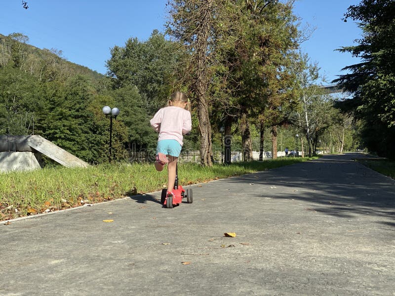 Jonge vrouw met scooter in het park stock afbeelding Jonge vrouw met scooter in het park stock afbeelding
