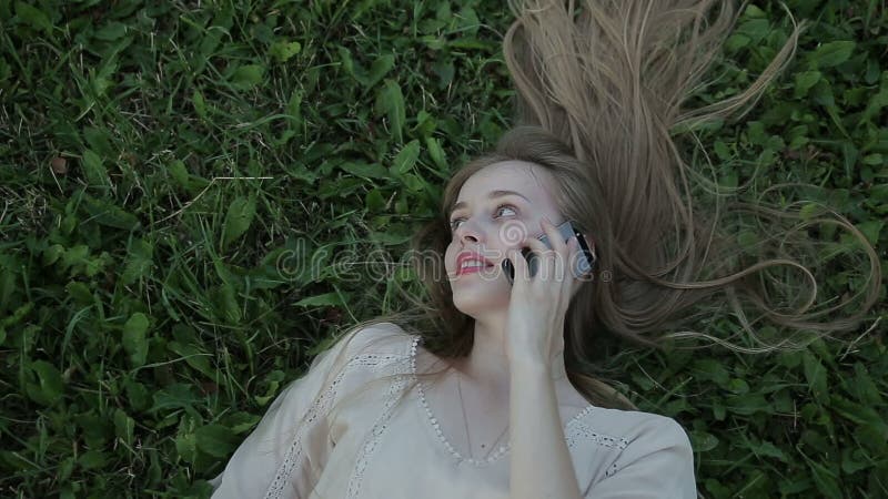 Jonge vrouw op telefoonzitting op het gras