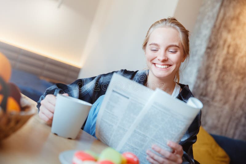 Jonge vrouw thuis in de keuken het drinken krant van de theelezing stock foto's Jonge vrouw thuis in de keuken het drinken krant van de theelezing stock foto's