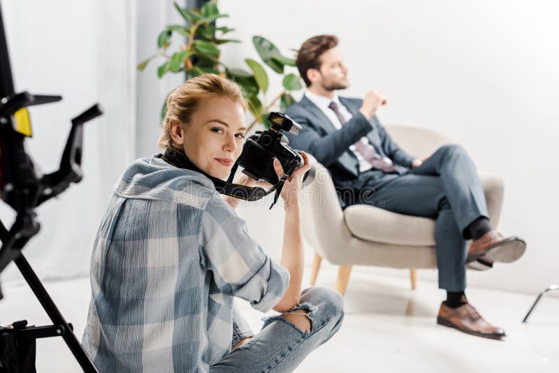 jonge vrouwelijke fotograaf die bij camera glimlachen terwijl het fotograferen van knappe zakenman royalty-vrije stock afbeelding jonge vrouwelijke fotograaf die bij camera glimlachen terwijl het fotograferen van knappe zakenman royalty-vrije stock afbeelding