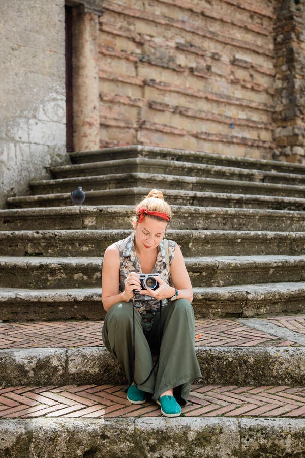 Young female traveler sitting on church steps holding retro film camera in Tuscany, Italy. Young female traveler sitting on church steps holding retro film camera in Tuscany, Italy