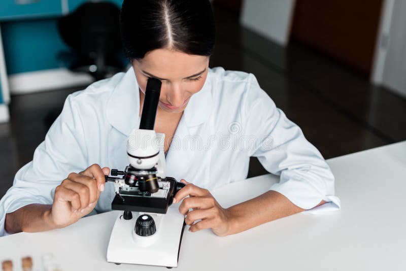 Jonge vrouwelijke wetenschapper die met microscoop in laboratorium werken royalty-vrije stock fotografie Jonge vrouwelijke wetenschapper die met microscoop in laboratorium werken royalty-vrije stock fotografie