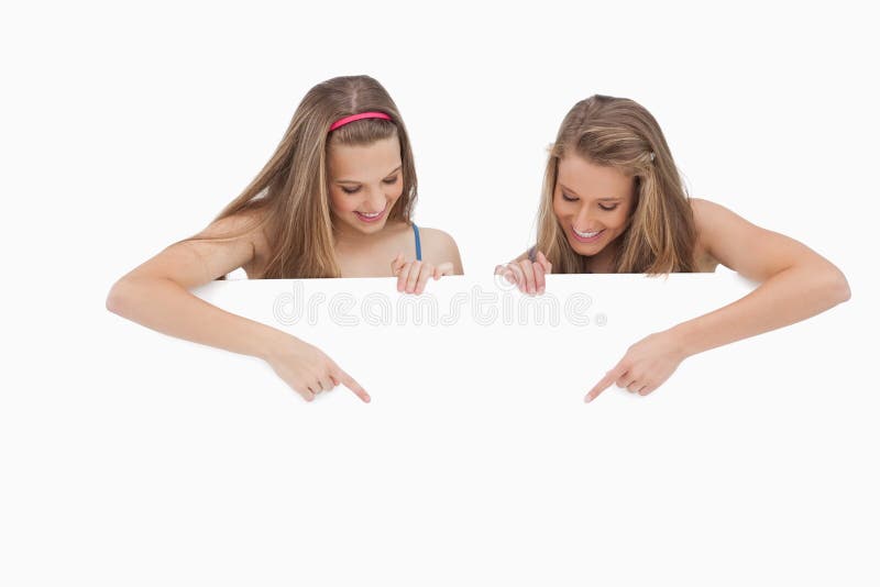 Jonge vrouwen die en een leeg teken houden richten stock fotografie Jonge vrouwen die en een leeg teken houden richten stock fotografie