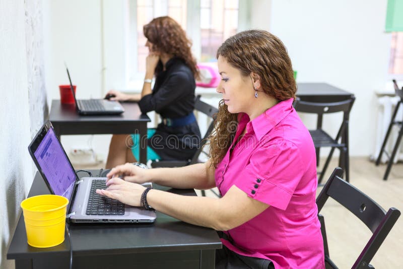 Jonge vrouwen die met laptops bij bureaus werken royalty-vrije stock fotografie Jonge vrouwen die met laptops bij bureaus werken royalty-vrije stock fotografie
