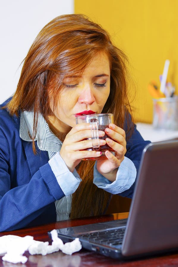 Jonge vrouwenzieken die met griep, door lijst zitten die computer met behulp van die, kijkend onwel en vermoeid, geneesmiddelen, royalty-vrije stock foto Jonge vrouwenzieken die met griep, door lijst zitten die computer met behulp van die, kijkend onwel en vermoeid, geneesmiddelen, royalty-vrije stock foto