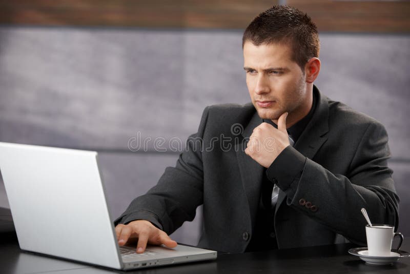 Jonge zakenman gebruikt laptop op kantoor royalty-vrije stock afbeeldingen