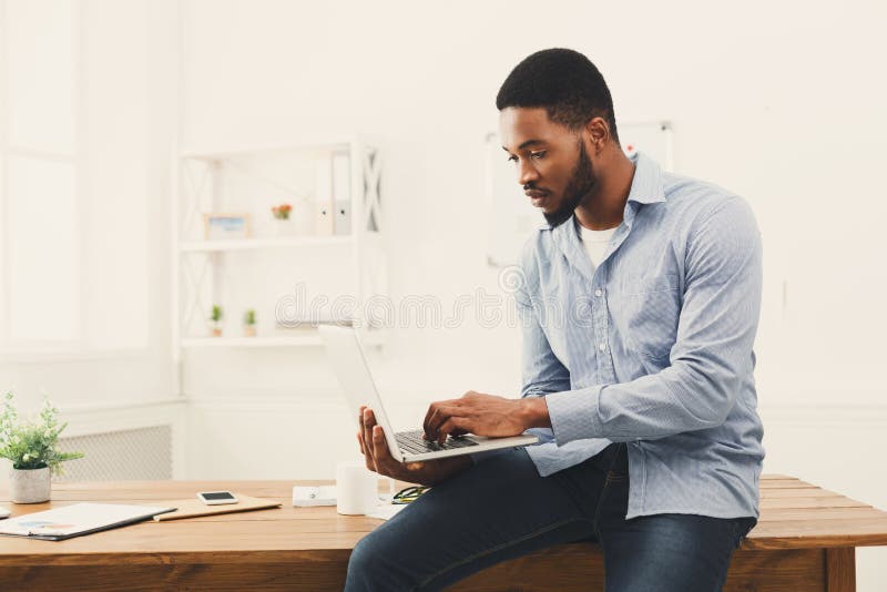 Jonge zwarte zakenman die aan laptop op kantoor werken stock foto Jonge zwarte zakenman die aan laptop op kantoor werken stock foto