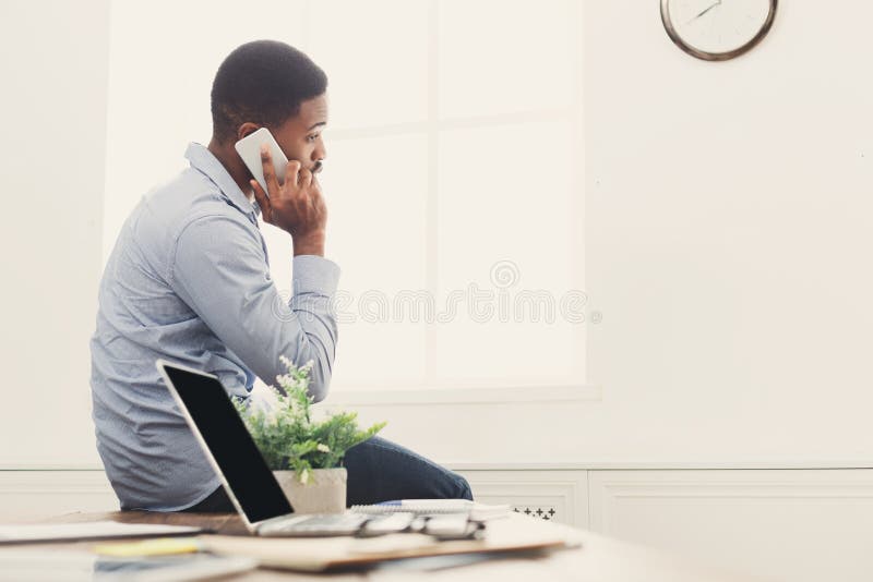 Jonge zwarte zakenman die telefoonbespreking hebben stock afbeelding Jonge zwarte zakenman die telefoonbespreking hebben stock afbeelding