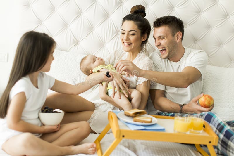 Jongelui familly op het bed stock afbeeldingen