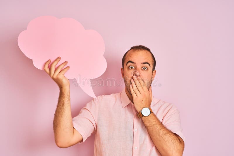 Young man holding cloud speech bubble standing over isolated pink background cover mouth with hand shocked with shame for mistake, expression of fear, scared in silence, secret concept. Young man holding cloud speech bubble standing over isolated pink background cover mouth with hand shocked with shame for mistake, expression of fear, scared in silence, secret concept