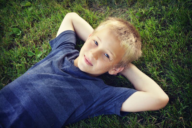 Jongen die in Gras liggen stock foto Jongen die in Gras liggen stock foto