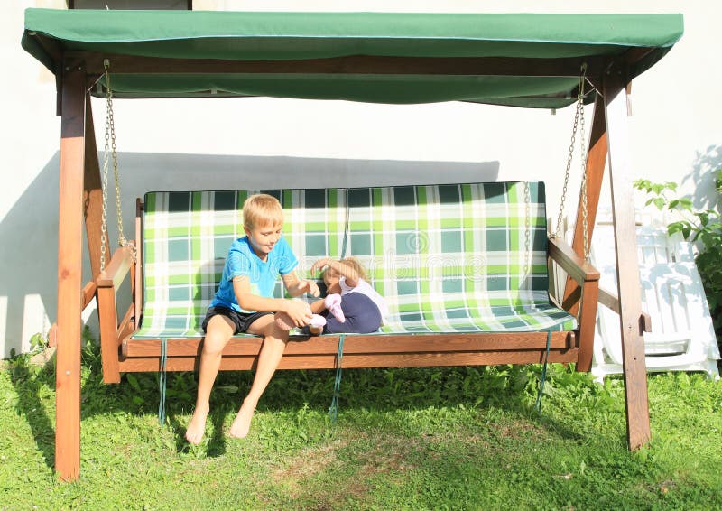 Jongen die meisje op een houten schommeling kietelen royalty-vrije stock fotografie Jongen die meisje op een houten schommeling kietelen royalty-vrije stock fotografie