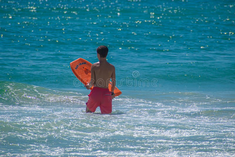 Daytona Beach Florida. July 07, 2019 Boy with surfboard enjoying waves at Main Street Pier area 3. Daytona Beach Florida. July 07, 2019 Boy with surfboard enjoying waves at Main Street Pier area 3