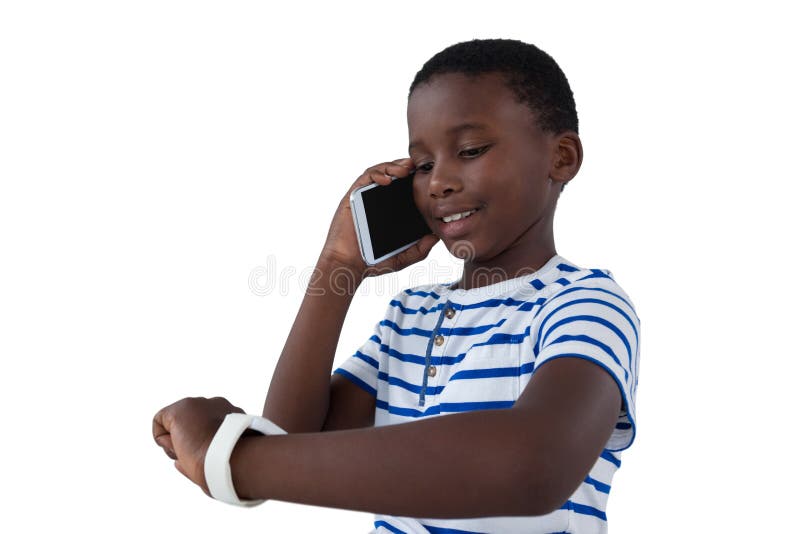 Jongen die zijn slim horloge bekijken terwijl het spreken op mobiele telefoon stock foto Jongen die zijn slim horloge bekijken terwijl het spreken op mobiele telefoon stock foto