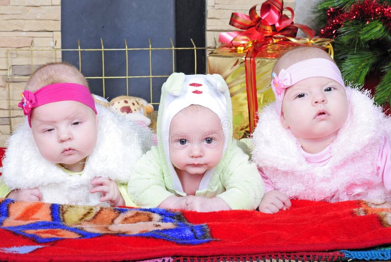 Jongen en de meisjes van Tweelingen dichtbij een Kerstboom stock foto Jongen en de meisjes van Tweelingen dichtbij een Kerstboom stock foto