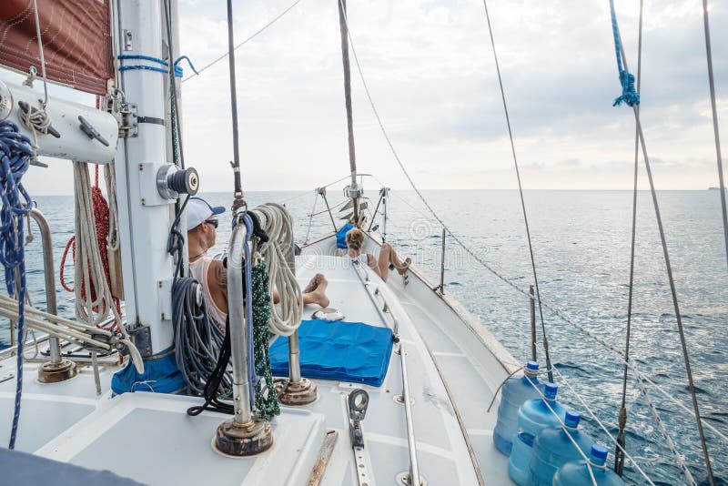 Jongen en meisje die op dek voor een zeilboot in Caraïbische Zee dichtbij Utila, Honduras, Midden-Amerika liggen stock afbeelding Jongen en meisje die op dek voor een zeilboot in Caraïbische Zee dichtbij Utila, Honduras, Midden-Amerika liggen stock afbeelding
