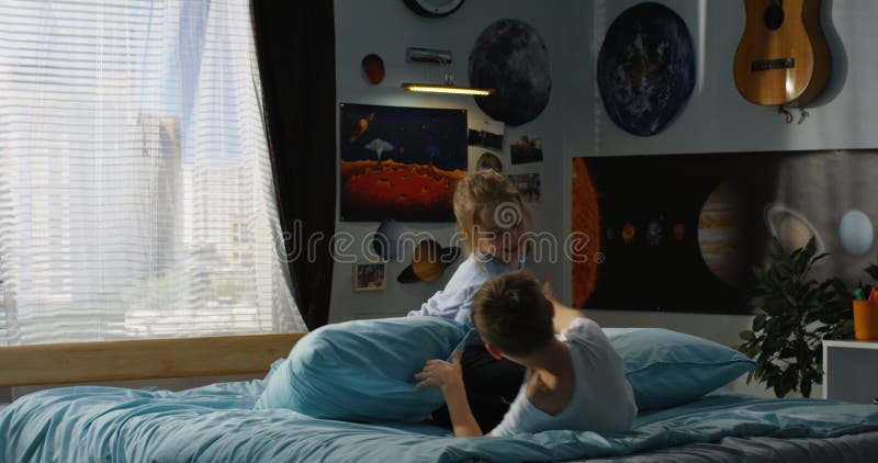 Jongen en meisjes speelhoofdkussenstrijd op bed stock fotografie Jongen en meisjes speelhoofdkussenstrijd op bed stock fotografie