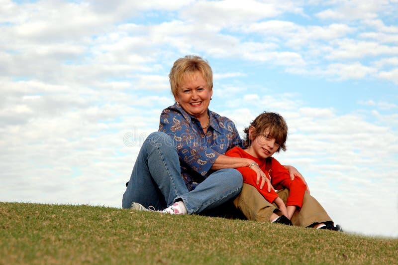 A boy and his grandmother sitting together outdoors on a hill. A boy and his grandmother sitting together outdoors on a hill